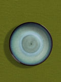 Assiette creuse en céramique émail bleu brume Céladon, sur fond coloré