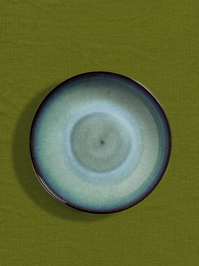 Assiette creuse en céramique émail bleu brume Céladon, sur fond coloré