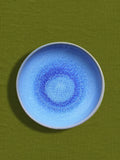 Assiette creuse en céramique émail bleu minéral Céladon, sur fond coloré