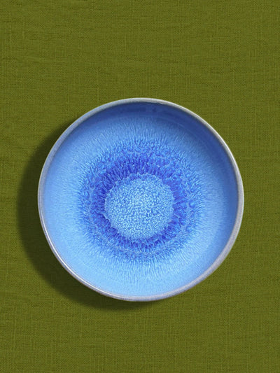 Assiette creuse en céramique émail bleu minéral Céladon, sur fond coloré