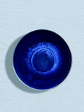 Assiette creuse en céramique émail bleu odyssée Céladon, sur fond coloré