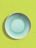 Assiette creuse en céramique émail vert minéral Céladon, sur fond coloré