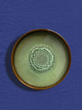 Assiette creuse en céramique émail vert rivage Céladon, sur fond coloré