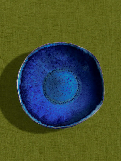 Assiette creuse Onda en céramique émail bleu abyssal Céladon, sur fond coloré