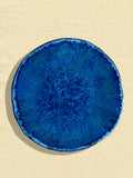 Grande assiette Onda en céramique émail bleu abyssal Céladon, sur fond coloré