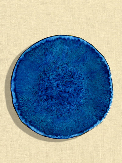 Grande assiette Onda en céramique émail bleu abyssal Céladon, sur fond coloré
