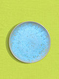 Petite assiette en céramique émail bleu água Céladon, sur fond coloré