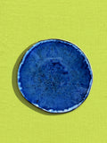Petite assiette Onda en céramique émail bleu abyssal Céladon, sur fond coloré