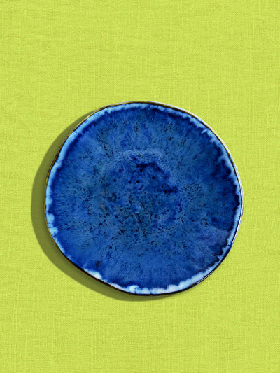 Petite assiette Onda en céramique émail bleu abyssal Céladon, sur fond coloré